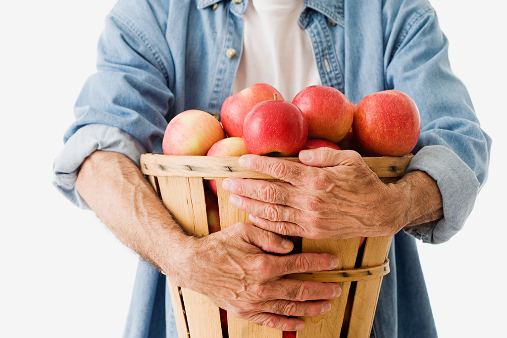 Man houdt mand met appels in handen.