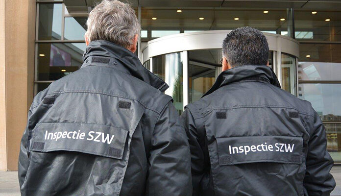 Twee inspecteurs van Inspectie SZW voor een gebouw