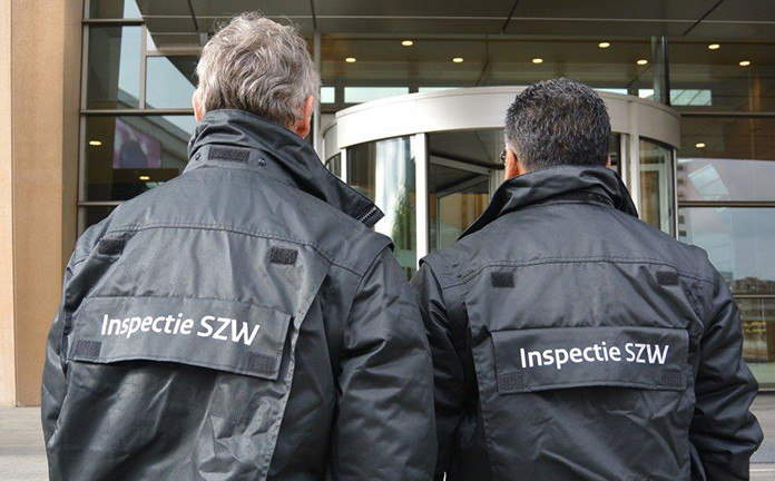 Twee inspecteurs van Inspectie SZW voor een gebouw