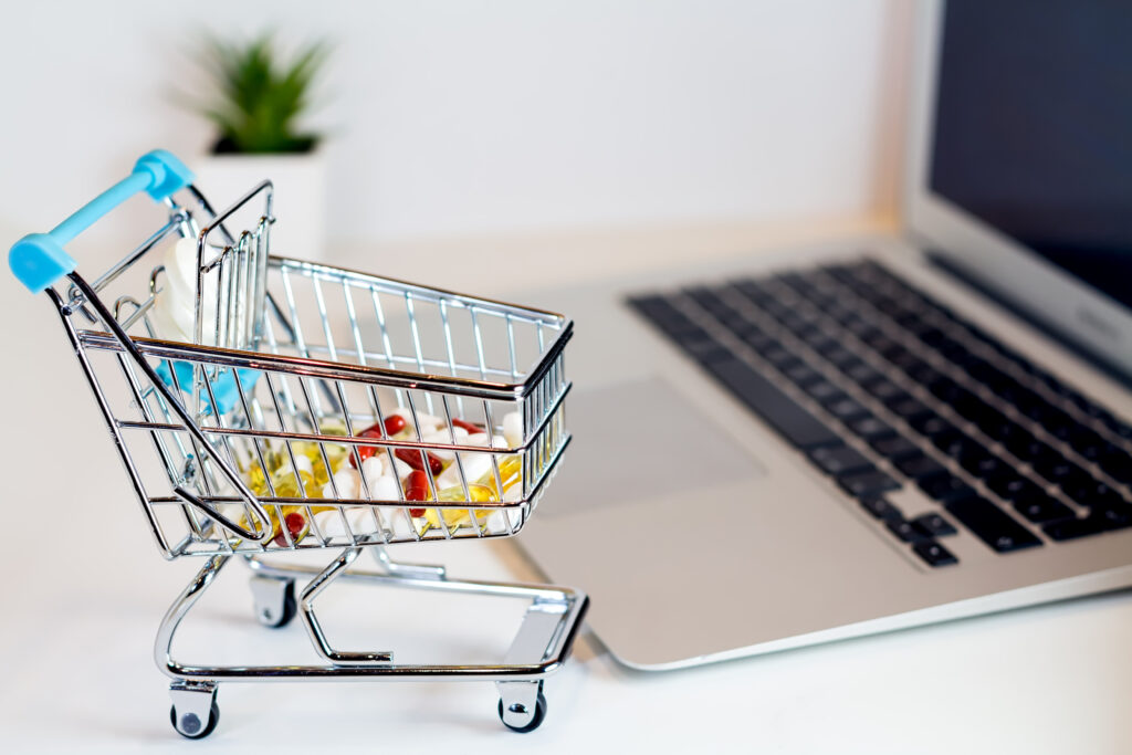 Winkelwagentje met medicijnen naast laptop