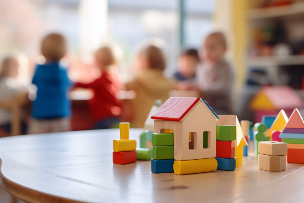 Kinderopvang met op de voorgrond een huisje gemaakt met blokken en op de achtergrond kinderen